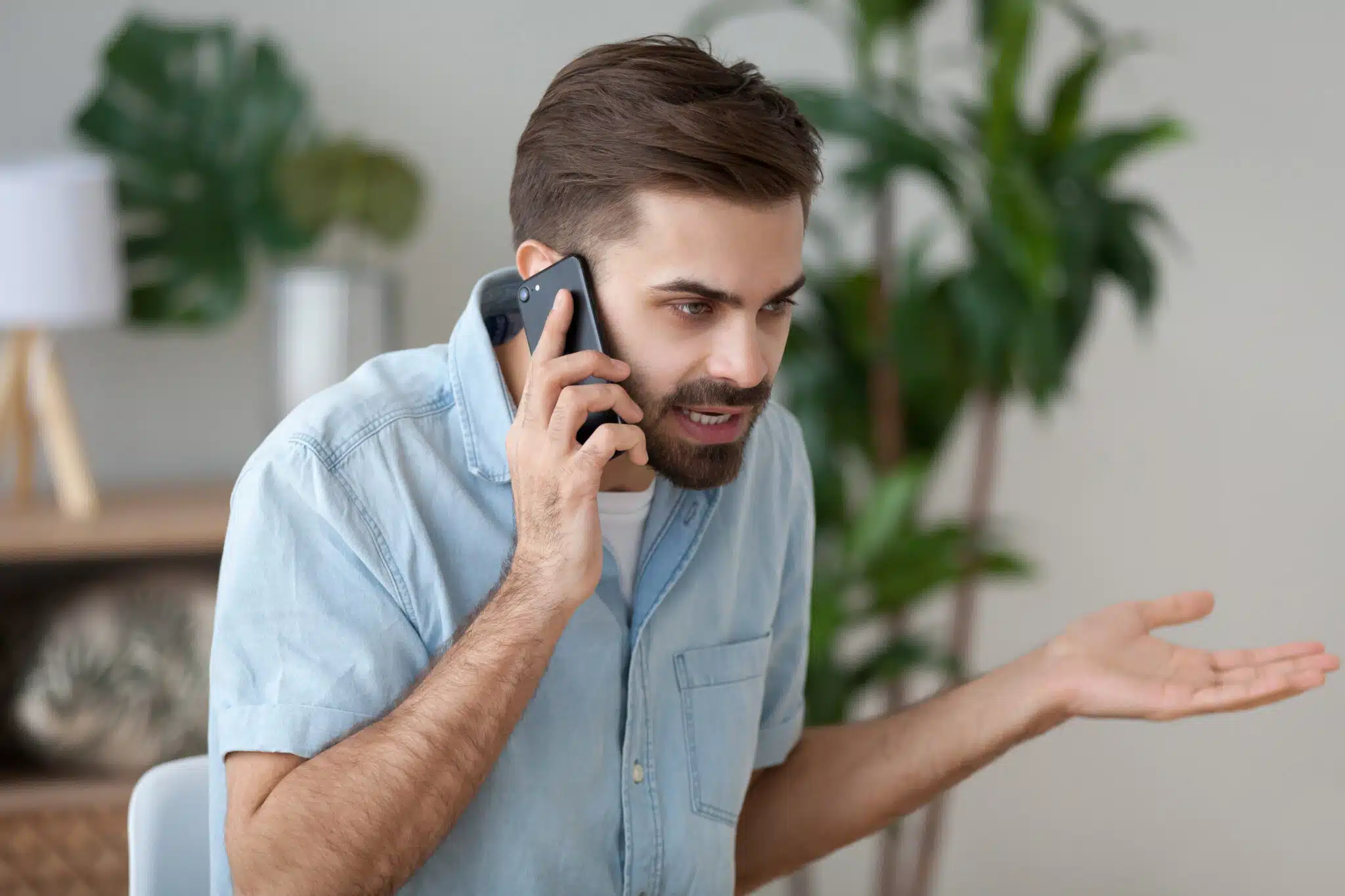 homme parlant au téléphone, exprimant son mécontentement dans un intérieur moderne