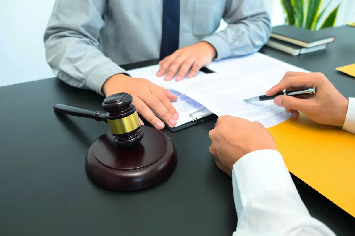 deux professionnels du droit signant un document avec un marteau de juge sur le bureau