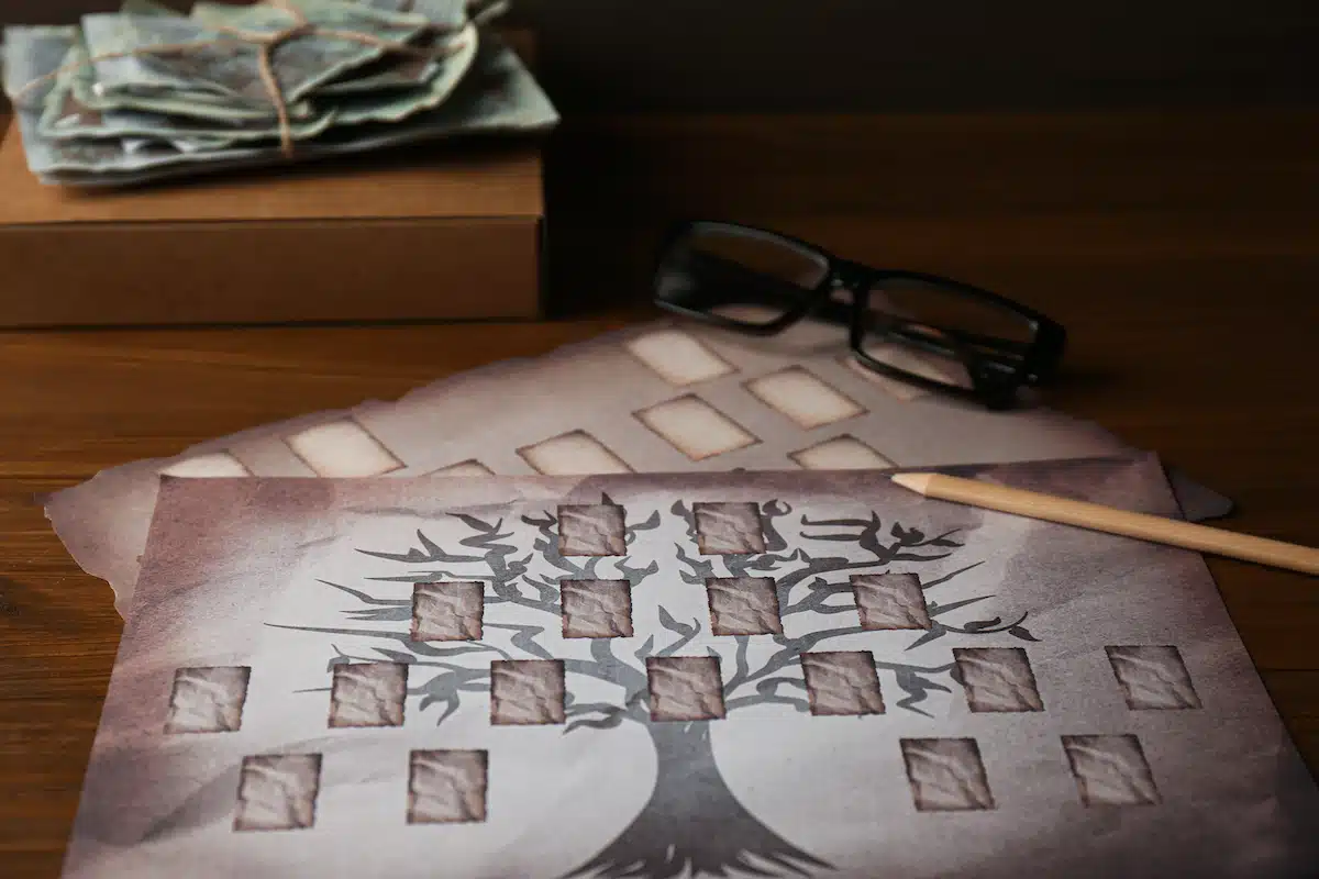 généalogiste travaillant sur un arbre généalogique successoral avec documents et lunettes