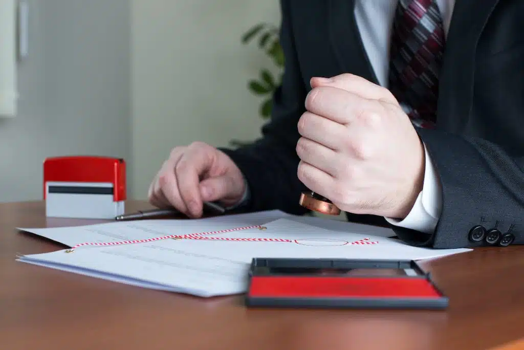 homme en costume tamponnant un document officiel avec un cachet rouge