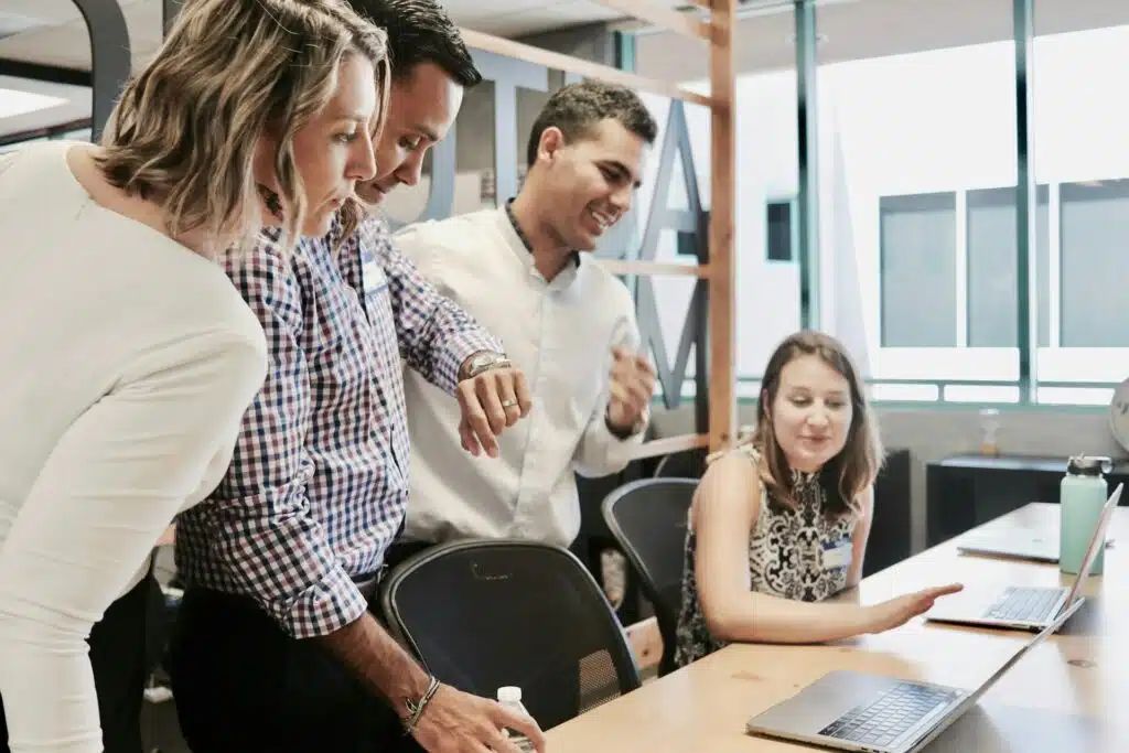 Un groupe de personnes dans un bureau s'engageant dans le processus d'acquisition tout en regardant un ordinateur portable.