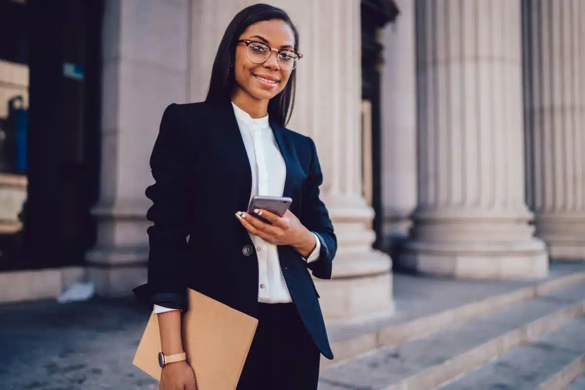 Une femme du Brouillon tenant un téléphone portable devant un immeuble.