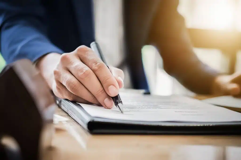 Un homme d'affaires signant soigneusement un document avec un stylo.