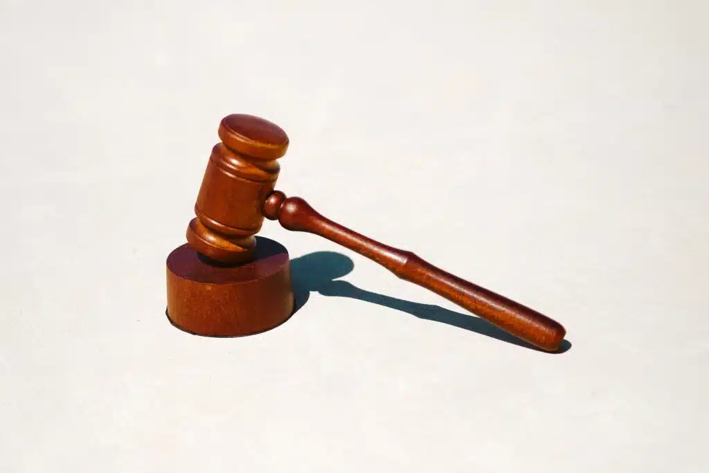Un marteau en bois adapté à la notion de subordination juridique, posé sur une surface blanche immaculée.