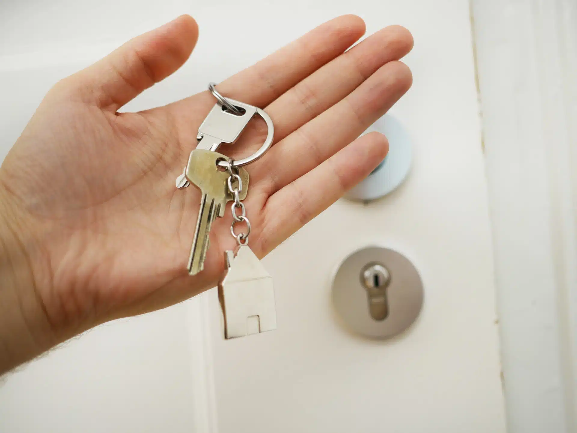 Une personne détenant la clé d'un bien en SCI devant une porte domiciliée.