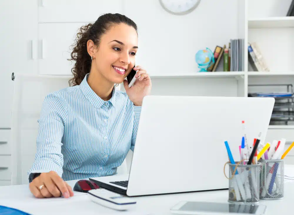 Une assistante administrative importante parlant au téléphone tout en étant assise à son bureau dans une entreprise.