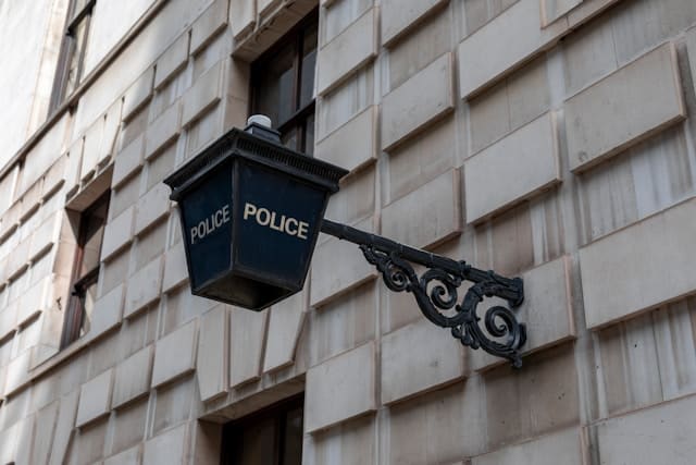 lanterne de police bleue accrochée à une façade de pierre grise
